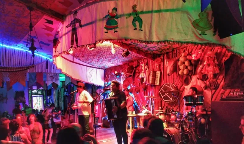Forró pé de serra ao vivo em casa típica de Aracaju, com sanfona e público dançando.
