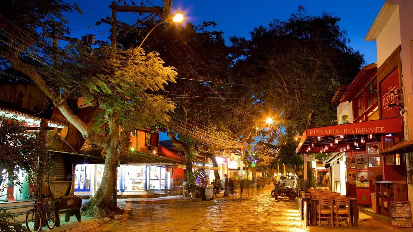 Rua das Pedras de Búzios à noite, com restaurantes, lojas e movimento.