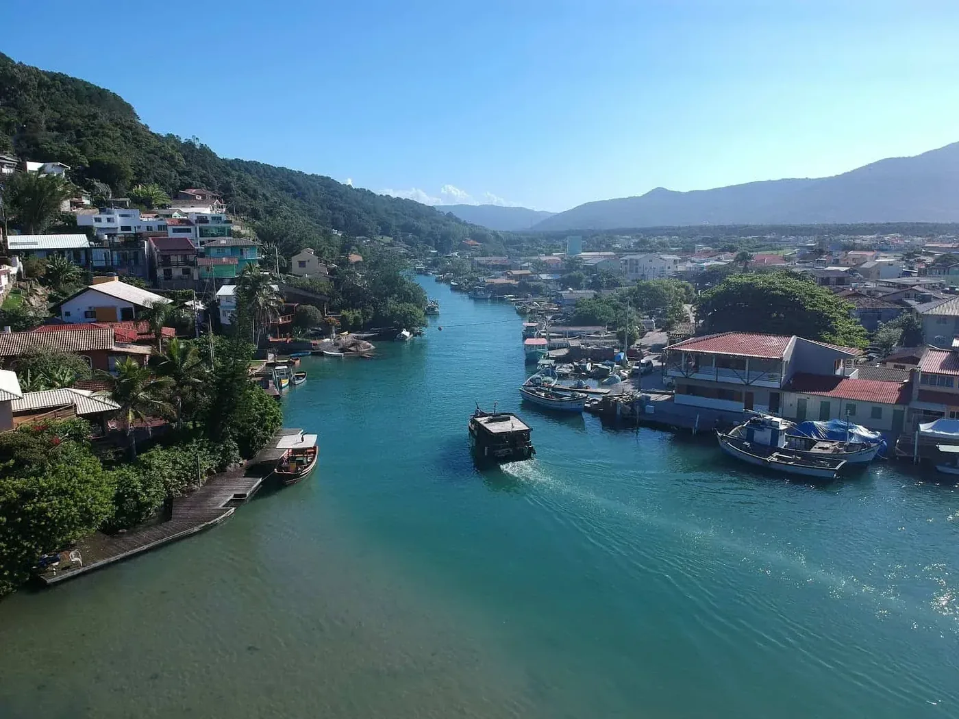 Vilarejo à beira do canal da Barra da Lagoa, em Florianópolis, com barcos de pesca.